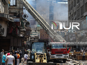 Pedestrians are in the street after the firefighters of the Civil Defense are controlling a huge fire that broke out in several stores, in M...