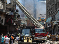 Pedestrians are in the street after the firefighters of the Civil Defense are controlling a huge fire that broke out in several stores, in M...