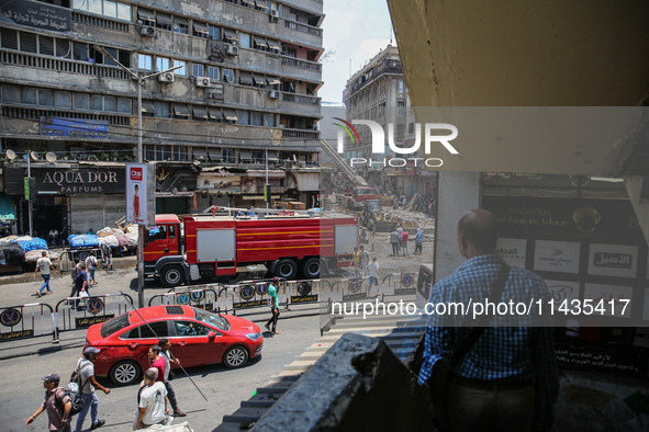 A pedestrian is looking at the fire after the firefighters of the Civil Defense are controlling a huge fire that broke out in several stores...