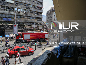 A pedestrian is looking at the fire after the firefighters of the Civil Defense are controlling a huge fire that broke out in several stores...