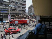 A pedestrian is looking at the fire after the firefighters of the Civil Defense are controlling a huge fire that broke out in several stores...