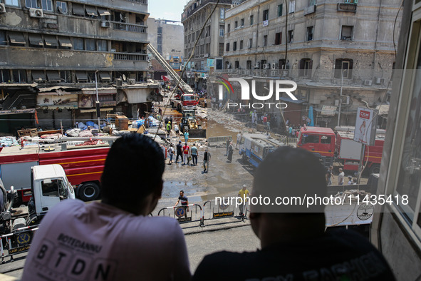 Pedestrians in a building are looking at the fire after the firefighters of the Civil Defense are controlling a huge fire that broke out in...