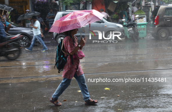 A woman with an umbrella is walking on a road during heavy monsoon rain in Kolkata, India, on July 26, 2024. 