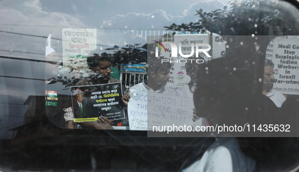 A woman is looking from a moving car window as Indians for Palestine group members are holding posters during a protest, amid the ongoing co...