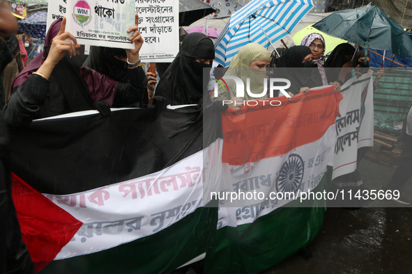 Muslim women wearing hijabs are holding posters and shouting slogans during a protest rally, amid the ongoing conflict in Gaza between Israe...