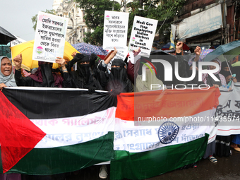 Muslim women are wearing hijabs, showing a slogan, and holding posters along with Palestine and Indian National Flags during a protest rally...