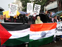 Muslim women are wearing hijabs, showing a slogan, and holding posters along with Palestine and Indian National Flags during a protest rally...