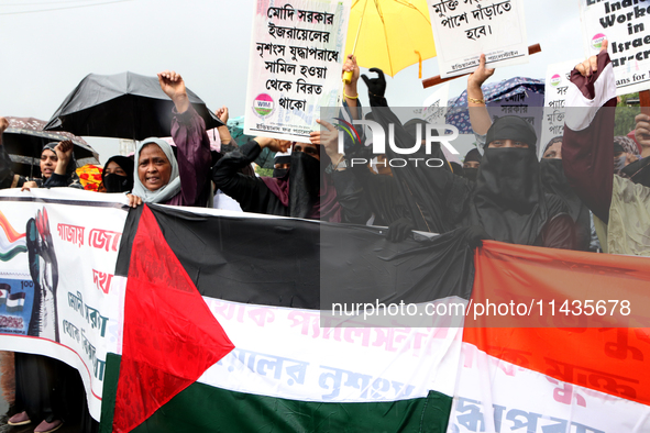 Muslim women are wearing hijabs, showing a slogan, and holding posters along with Palestine and Indian National Flags during a protest rally...