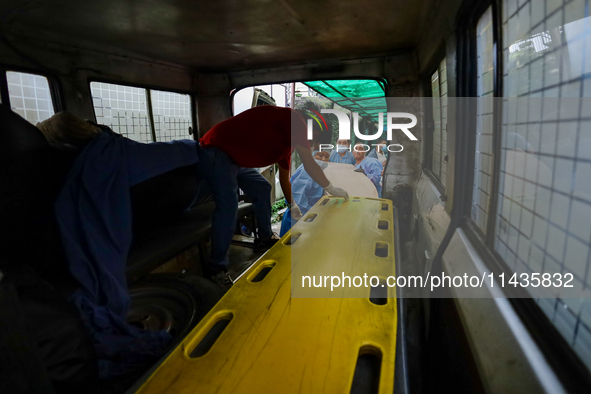 Dead body management officials are loading a coffin containing the body of a deceased in the Saurya Airlines crash into a hearse at a morgue...