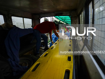 Dead body management officials are loading a coffin containing the body of a deceased in the Saurya Airlines crash into a hearse at a morgue...