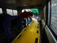 Dead body management officials are loading a coffin containing the body of a deceased in the Saurya Airlines crash into a hearse at a morgue...