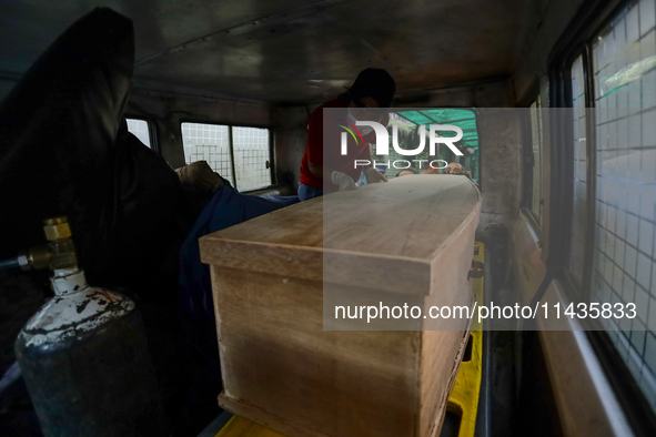 Dead body management officials are loading a coffin containing the body of a deceased in the Saurya Airlines crash into a hearse at a morgue...