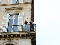 Two women are dancing on their balcony in front of the queues of people waiting to attend the opening ceremony of the Olympic Games. (