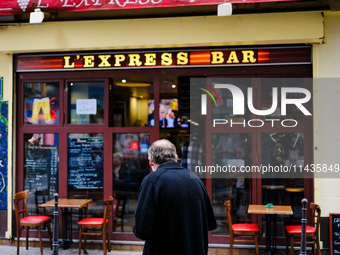 A man is watching the opening ceremony of the Paris Olympic Games from a Parisian bar television on the street. (