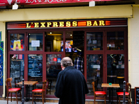 A man is watching the opening ceremony of the Paris Olympic Games from a Parisian bar television on the street. (