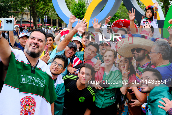 Mexican fans are taking pictures in front of the Olympic rings on the day of the opening ceremony of the Paris Olympics. 