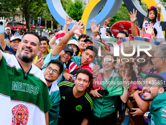 Mexican fans are taking pictures in front of the Olympic rings on the day of the opening ceremony of the Paris Olympics. (