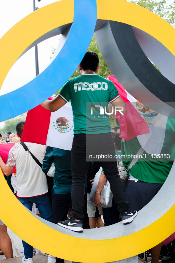 A Mexican supporter is standing in an Olympic ring on the Place de la Bastille in Paris. 