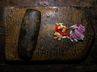 A woman is pounding masala in a heavy Shil Nora (Batan and Una) in Tehtatta, West Bengal, India, on July 15, 2024. (