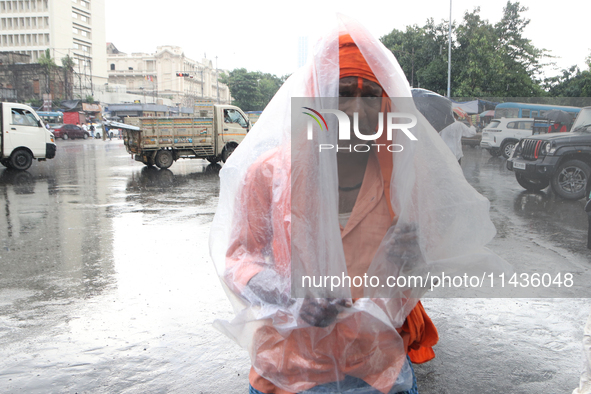 A laborer is covering themselves with plastic sheets to protect themselves from the monsoon rain in Kolkata, India, on July 26, 2024. 