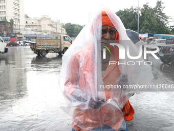 A laborer is covering themselves with plastic sheets to protect themselves from the monsoon rain in Kolkata, India, on July 26, 2024. (