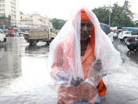 A laborer is covering themselves with plastic sheets to protect themselves from the monsoon rain in Kolkata, India, on July 26, 2024. (