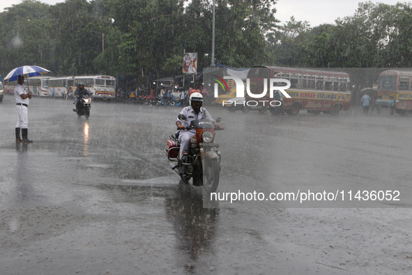 A traffic sergeant is riding an Enfield Bullet Bike in the monsoon rain in Kolkata, India, on July 26, 2024. 