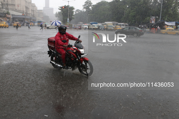 A Zomato food delivery boy is driving a bike in the heavy rain in Kolkata, India, on July 26, 2024. 