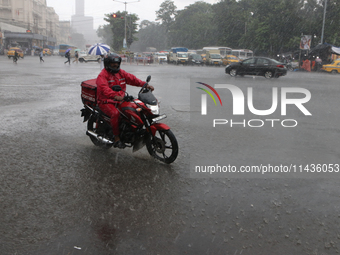 A Zomato food delivery boy is driving a bike in the heavy rain in Kolkata, India, on July 26, 2024. (