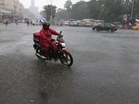 A Zomato food delivery boy is driving a bike in the heavy rain in Kolkata, India, on July 26, 2024. (