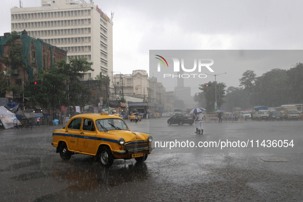 A Yellow Ambassador Taxi is riding in the heavy rainfall in Kolkata, India, on July 26, 2024. 