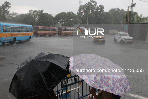 People are holding umbrellas as they are walking in the monsoon rain in Kolkata, India, on July 26, 2024. 