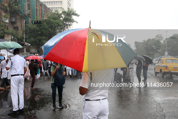 The police are holding umbrellas as they are walking in the monsoon rain in Kolkata, India, on July 26, 2024. 