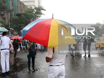 The police are holding umbrellas as they are walking in the monsoon rain in Kolkata, India, on July 26, 2024. (