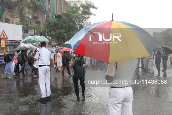 The police are holding umbrellas as they are walking in the monsoon rain in Kolkata, India, on July 26, 2024. 