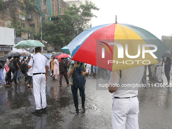 The police are holding umbrellas as they are walking in the monsoon rain in Kolkata, India, on July 26, 2024. (