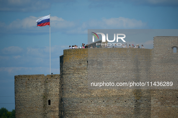 Visitors are seen on a tower of the Ivangorod Fortress with a Russian flag flying accross the river in Narva, Estonia on 24 July, 2024. Esto...