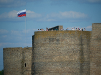 Visitors are seen on a tower of the Ivangorod Fortress with a Russian flag flying accross the river in Narva, Estonia on 24 July, 2024. Esto...