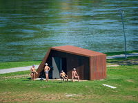 People are seen sunbathing on the banks of the Narva River in Narva, Estonia on 24 July, 2024. Estonian authorities have closed the bridge t...