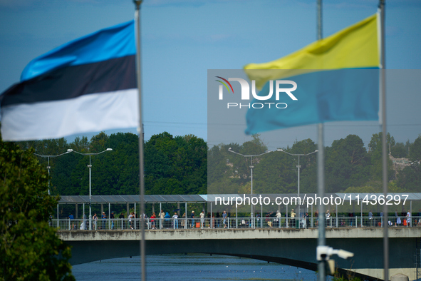 People are seen crossing the border with Russia with Estonia and Ukraine flags flying in Narva, Estonia on 24 July, 2024. Estonian authoriti...