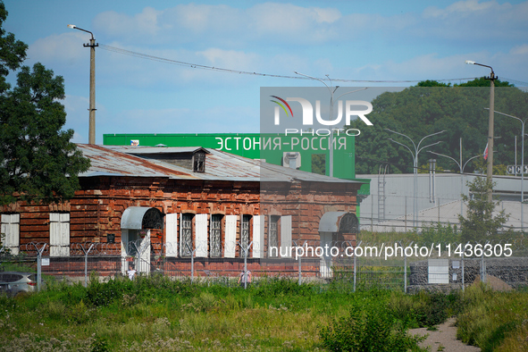 A building with the words ''Estonia-Russia'' is seen in Ivangorod, Russia with people looking on in the foreground in Narva, Estonia on 24 J...