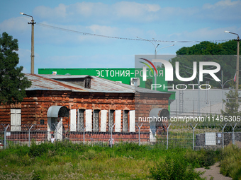 A building with the words ''Estonia-Russia'' is seen in Ivangorod, Russia with people looking on in the foreground in Narva, Estonia on 24 J...