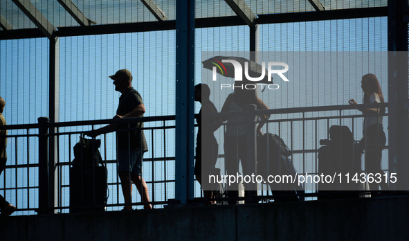 People waiting to cross the border to Russia are seen on the Frienship Bridge from the bank of the Narva River in Narva, Estonia on 24 July,...