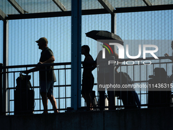 People waiting to cross the border to Russia are seen on the Frienship Bridge from the bank of the Narva River in Narva, Estonia on 24 July,...