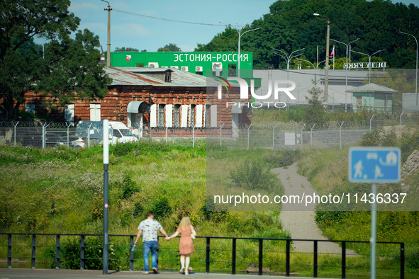 A building with the words ''Estonia-Russia'' is seen in Ivangorod, Russia with people looking on in the foreground in Narva, Estonia on 24 J...