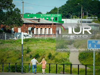 A building with the words ''Estonia-Russia'' is seen in Ivangorod, Russia with people looking on in the foreground in Narva, Estonia on 24 J...