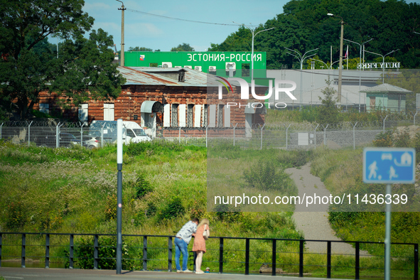 A building with the words ''Estonia-Russia'' is seen in Ivangorod, Russia with people looking on in the foreground in Narva, Estonia on 24 J...