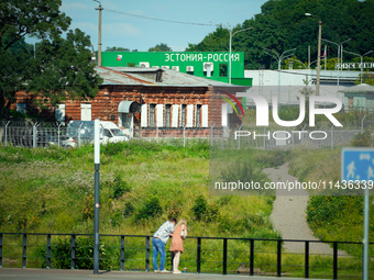 A building with the words ''Estonia-Russia'' is seen in Ivangorod, Russia with people looking on in the foreground in Narva, Estonia on 24 J...