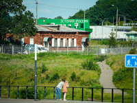 A building with the words ''Estonia-Russia'' is seen in Ivangorod, Russia with people looking on in the foreground in Narva, Estonia on 24 J...