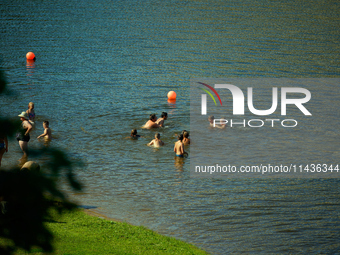 People are seen in the Narva River in Narva, Estonia on 24 July, 2024. Estonian authorities have closed the bridge that connects Russia and...